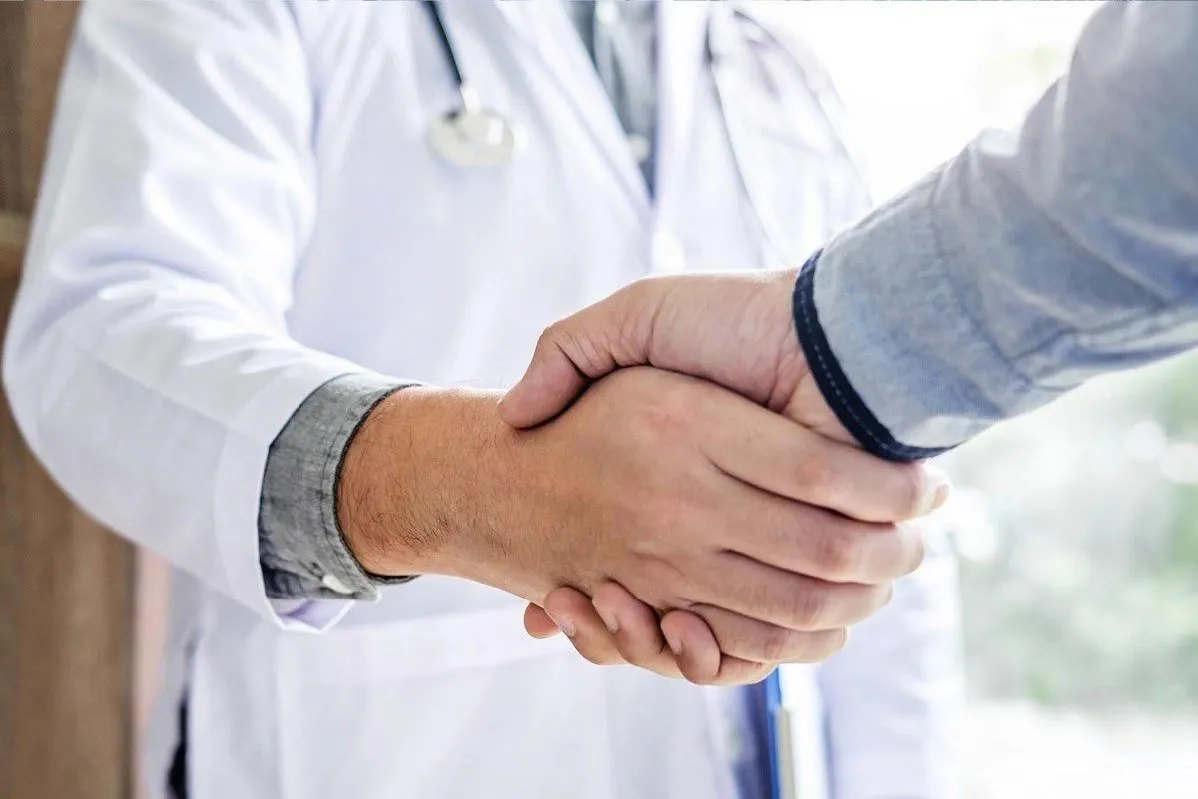 A doctor and a patient shaking hands, symbolizing trust and agreement in medical care.